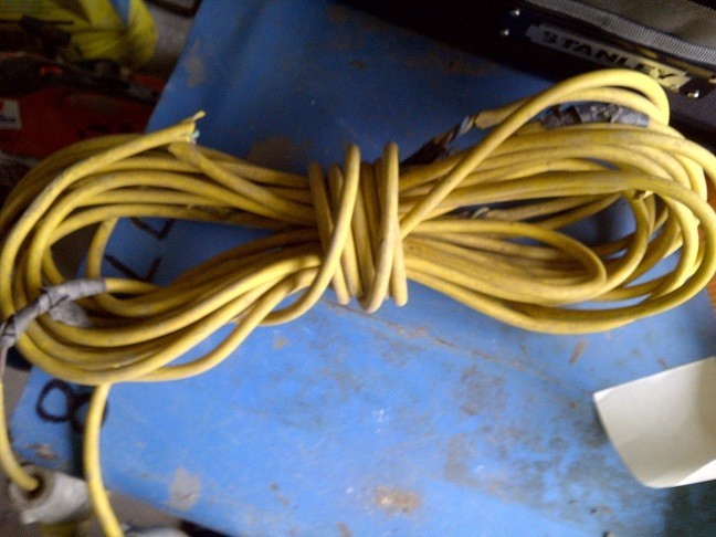 110volt power lead with lots of damage sitting on a blue welding unit