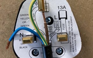Plug showing coloured wires from the cord and the wiring diagram to guide someone to wire a plug correctly; as in portable appliance testing
