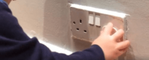 electric socket cover being pulled out of a socket by a small child