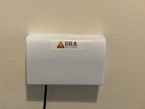 Double socket protected with a latched socket cover, with a DRA PAT Testing sticker on