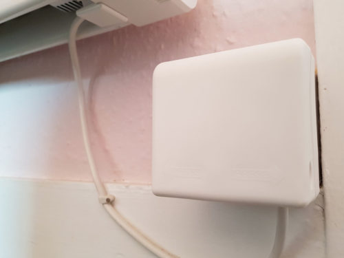 An closed socket cover over a timer switch for a fan system on a pink wall