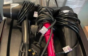 2 hair dryers and a set of red hair straighteners from a hair salon pat testing job that we did in 2021 showing 3 passed PAT testing labels