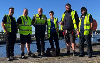 The full DRA PAT testing 6 man team pictured on the banks of the River Tyne at Wallsend, Looking to Newcastle upon Tyne. PAT Testing Newcastle and North East