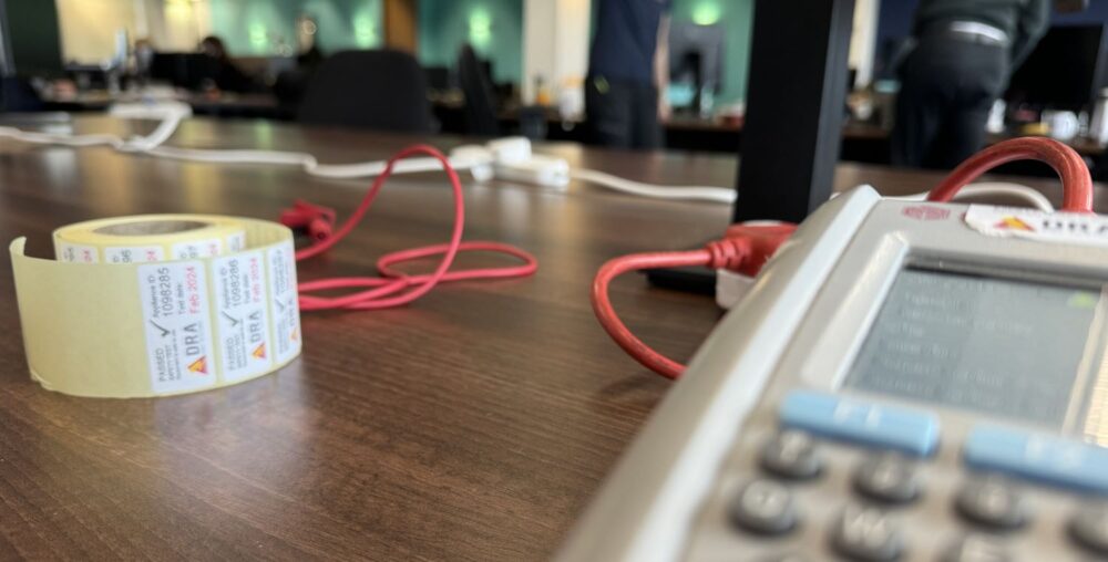 Seaward Apollo PAT Tester 2 PAT testing electrical equipment in an office - image showing PAT tester, labels and extension lead being tested