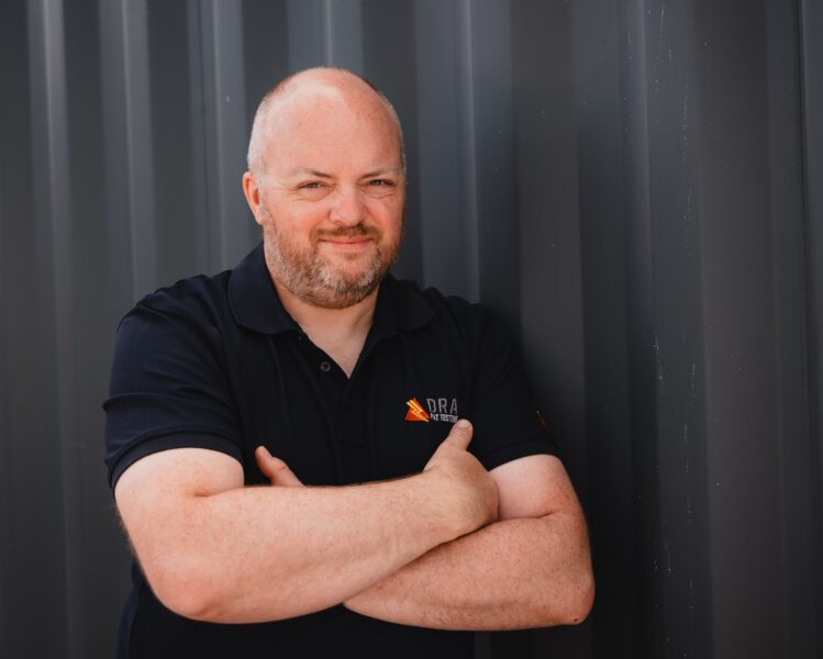 Richard Ayre, owner, DRA PAT Testing. Photograph of Richard standing in front of a shipping container in Newcastle upon Tyne